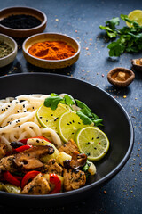 Chicken nuggets with noodles and stir fried vegetables on black table
