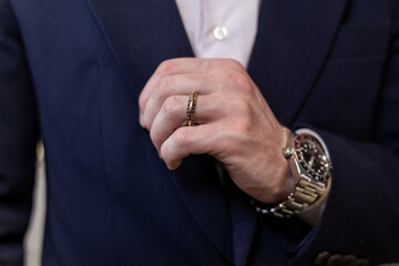 Close-up shot in a jewelry boutique man's hand adorned with a wedding ring from yellow and white...