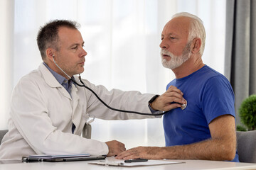 Doctor cardiologist examining senior male patient by listening and checking heartbeat using...