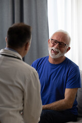 Healthy smiling senior patient feeling cheerful about good news at medical consultation. Happy eldelrly man talking to a doctor at appointment. - 602219792