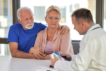 Senior couple at doctor medical consultation visit. Healthcare worker discusses health problems with elderly spouses - 602219938