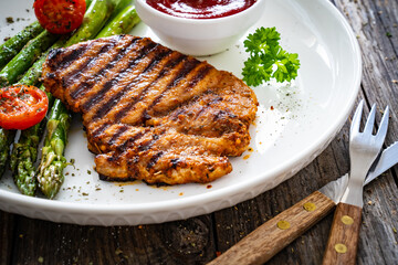Barbecued meat and asparagus on wooden table