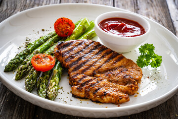 Barbecued meat and asparagus on wooden table