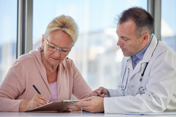 Senior woman filling insurance or other legal document at appointment with doctor. Elderly patient signing medical treatment contract, agreement form for medical care service, consultation, therapy