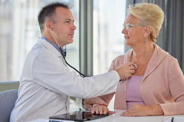 Doctor cardiologist examining senior female patient by listening and checking heartbeat using...