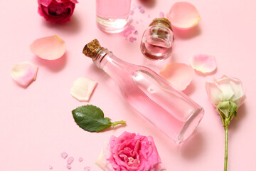 Obraz na płótnie Canvas Bottles of cosmetic oil with rose extract and flowers on pink background
