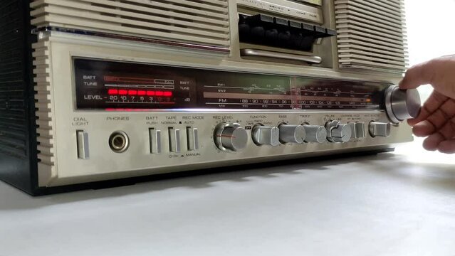 radio needle tuning to search for broadcasts ,80s boombox operated manually by hand old style music listening concept