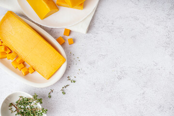 Plate with tasty cheddar cheese on light background