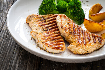 Barbecued turkey breast and broccoli on wooden table 