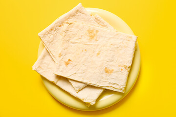 Plate with fresh thin lavash on yellow background