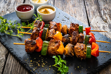Meat skewers - grilled meat with vegetables on wooden background
 - Powered by Adobe