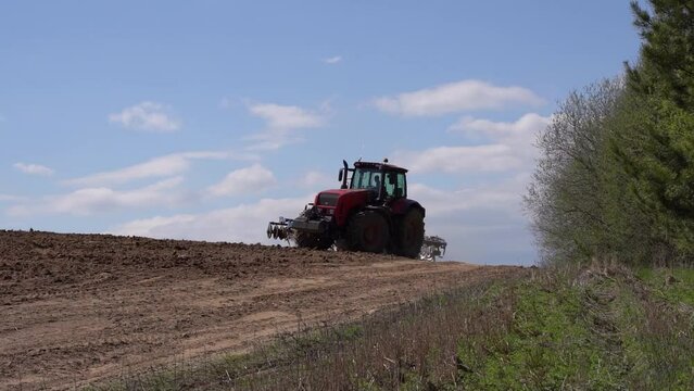 Tractor on the farmer's field plows and cultivates the soil. Agriculture, farming business harvest concept.