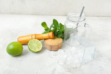 Mason jar, mortar and ingredients for preparing mojito on light background