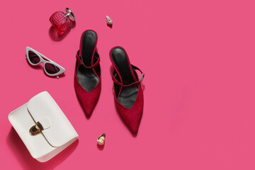 Red suede heels with sunglasses, perfume and bag on pink background