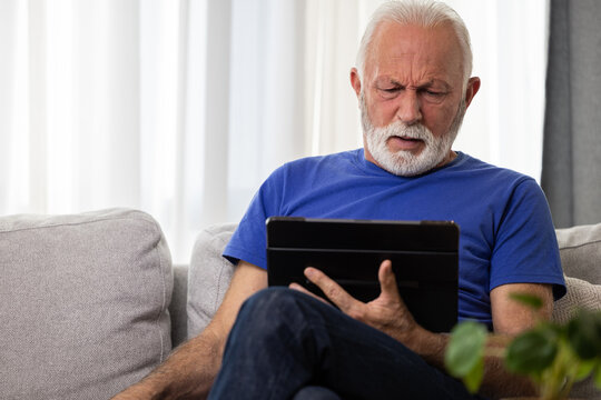 Shocked frustrated senior mature man reading shocking online news at home. Stressed worried elderly male confused by bad news or computer problem