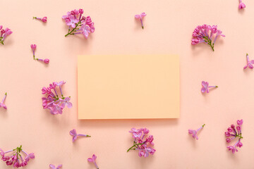 Blank card and beautiful lilac flowers on pale pink background