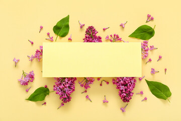 Blank card and beautiful lilac flowers on pale yellow background