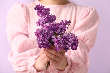 Young woman with bouquet of lilac flowers on purple background