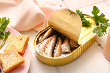 Canned smoked sprats with parsley on white tile background