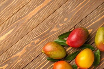 Fresh ripe mangoes on wooden background