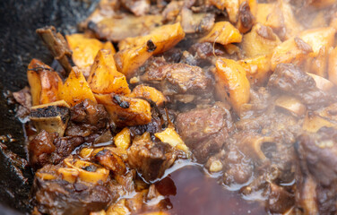 Cooking stewed beef in cauldron at street food festival