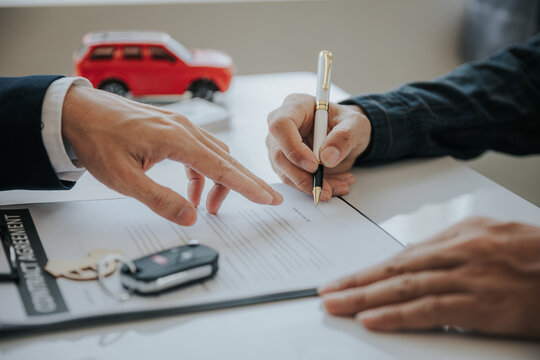 Closing Sale. Asian Customer Signing Car Insurance Paperwork Or Lease Contract Or Agreement. Buy Or Sell A New Or Used Car With Car Keys On The Table.