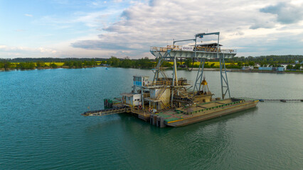 Industrial boat floating on the lake. Boat in the middle of the lake. Water background. Boat from mining industry. 