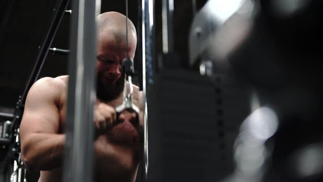 Unleashing the power of triceps. bodybuilder sculpting impressive triceps muscle with intense cable exercises. slow motion