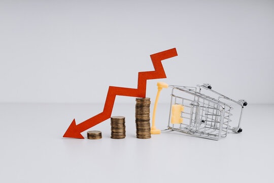 Global crisis inflation and rising prices. Small shopping cart with stacked coins and red arrow down