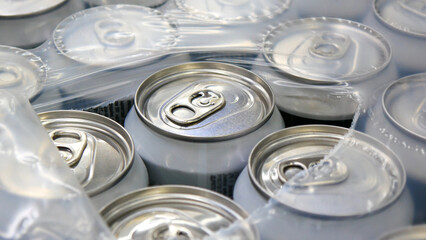 Close-up of many white cans of beer in plastic packaging torn from the top