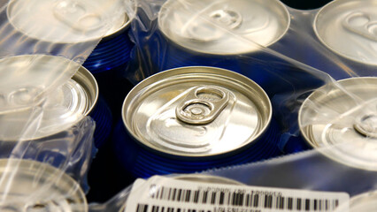 Close-up of many blue cans of beer in plastic packaging torn from the top