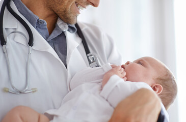 Doctor, pediatrician and holding baby in arms for hospital assessment, medical support and growth. Pediatrics, happy physician and carrying newborn kid in clinic, healthcare service and help children