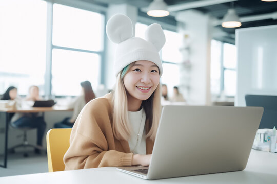 A business-focused Asian girl works on her laptop in a modern co-working space, while wearing a fun rabbit knit hat that adds a touch of unique style. generative AI.