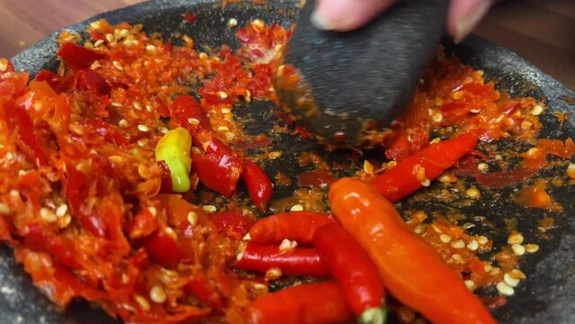 the process of making Indonesian sambals using a traditional stone grinder or mortar and pestle