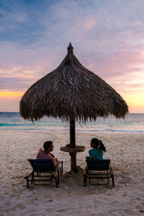 A couple of men and women are on the beach watching the sunset during vacation at Aruba Island Caribbean. 