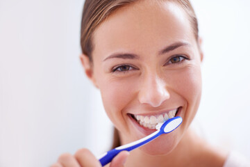 Young woman, portrait and brushing teeth in bathroom with smile, health or self care for hygiene,...