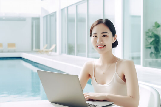 An attractive Asian girl balances work and play as she types away on her laptop while lounging in her swimsuit at a modern destination. generative AI.