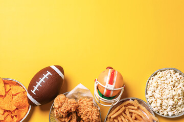 Top view of snacks for watching a football game with copy space over yellow background. Super bowl...
