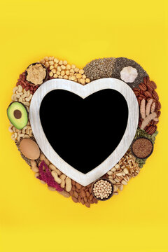Health food high in lipds. Ingredients with unsaturated fats for healthy heart and low cholesterol levels with nuts, seeds, vegetables, dairy and grain. Chalk board blackboard wreath on yellow.