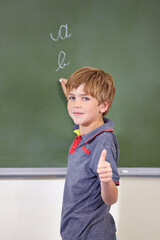 Portrait, child and student with thumbs up on blackboard in classroom, elementary school and mockup. Chalkboard, education and kid with hand gesture for like emoji, agreement and learning to write.