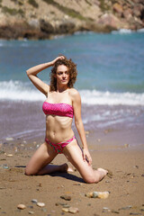 Fototapeta premium Sensual woman posing on sandy beach near sea