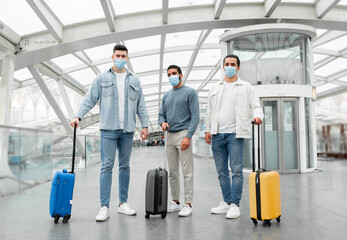 Fototapeta na wymiar Three Travelers Men Wearing Face Masks For Protection In Airport