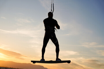 silhouette of a person doing a kite surfing jump at sunset in summertime holidays