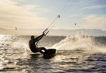 silhouette of a person doing a kite surfing in the lagoon. Summertime water sport