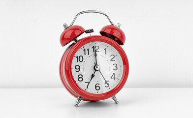 Red alarm clock on white wall background