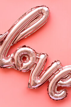 Love made from foil balloons on pink. Monochrome image.