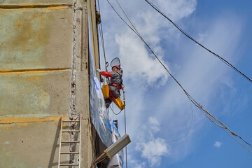 Rope access is a high-risk job. A man works on ropes.