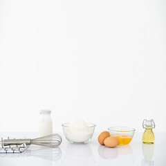 Kitchen background for mockup with eggs, rolling pin,whisk, bowl for cooking and baking utensils on table on white background . Front view, recipe theme.
