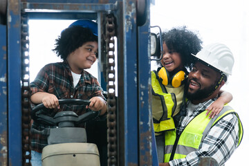 Cute African little child boy role playing engineer wear safety hat sitting on forklift at warehouse while father who is foreman holding daughter, smiling looking at his son. Family time at workplace © Pruksachat