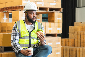 African middle aged engineer worker beard man wear safety hat, eating burger, coffee in lunch break...
